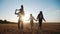 People in the park. happy family silhouette walk at sunset. mom dad and daughters walk holding hands in the park. happy