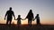 People in the park. happy family silhouette walk at sunset. mom dad and daughters walk holding hands in the park. happy