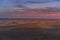 People passing through sand dunes overlooking the ocean on the horizon during a sunny day with thick clouds moving in the sky from