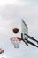 People play basketball outdoors. Hands in the frame. The ball flies into the basket. Vertical shot.