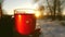 People pour a hot drink from a thermos into a glass at the sunset of the bright sun.