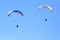 People practicing paragliding in a blue sky XI