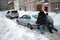 People pushing stuck car in snowy street