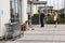 People queue for a cashpoint or ATM while a homeless man sits on the floor next to them