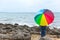 People with rainbow umbrella at the seashore