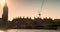 People and red buses crossing Westminster Bridge at sunset by Big Ben and the Houses of Parliament, London, England