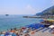 People relaxing, colorful umbrella on the beach on a sunny day, on the coast of Amalfi, Italy. A ship, a liner in the blue sea.