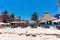 People relaxing on deck chair with canopy on beach against restaurant