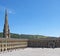 People relaxing and enjoying the summer sunshine in the square of halifax piece hall in west yorkshire with surrounding hills and