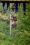 People ride on a cable car. The legs of passengers hang over the mountain forest