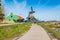 People riding bicycles, houses and windmill in Zaanse Schans, Holland