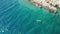 People row colorful kayak along sea past rocky beach