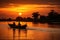 People rowing a canoe down a lake at sunset