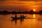 People rowing a canoe down a lake at sunset