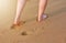 People`s feet walking along the fine sand beach.