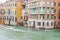 People sailing boats and water taxis beside gothic Venetian buildings on a rainy November day on the Grand Canal waterway, Venice