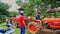 People at Scooters Surround Tractor with Trailer in Village