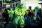 People in shiny green demon costume pass by city street at dominican carnival