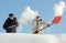 People shovelling snow on a roof