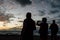 People in silhouette enjoying and taking picture with mobile phone at beautiful sunset at the beach - concept of friends and