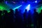 People silhouettes on dance floor of night club to laser projectors