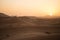 People silhouettes strolling through the dunes of the Sahara desert during sunset