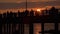 People silhouettes walking along the pier at dramatic sunset on hot summer day in Palanga beach, Lithuania. Colourful sun setting