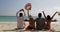 People sitting on beach talking happy raised hands back rear view, men and women communication tourists group on summer