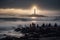 people sitting on the beach, watching a lighthouse beam light over the waves