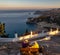 People sitting on bench at old Panagia Tsambika monastery and looking on wonderful landscape with Aegean sea and greek country at