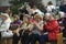 People sitting on benches on a rural lawn during concert devoted to the Day of village