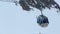 People sitting in cable car, moving up towards skiing run in snowy mountains