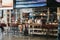 People sitting at a cafe, waiting for their trains under the departure board inside St. Pancras station, London, UK.