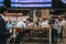 People sitting at a cafe, waiting for their trains under the departure board inside St. Pancras station, London, UK.