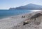 People sitting at the destroyed beach between heaps of stone after storm Gloria in January 2020 with mountain view, Albir, Spain