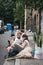 People sitting on the ground on Erza Street, relaxing after visiting Columbia Road Flower Market, London, UK.