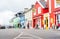 People sitting outside bar and walking past shop front of different bright colors in tourist and fishing town