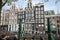 People sitting at sidewalk cafe by canal with facades of traditional houses in background. Amsterdam, Netherlands