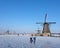 people skate on the ice near kinderdijk with al lot of windmills in holland on sunny winter day