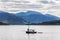 People in a small sailing boat in front of the small village of Ullapool in the Highlands in Scotland