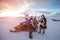 People with snowmobile in desert of frozen north at sunset