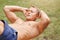 People, sport, lifestyle and endurance concept. Sporty young male bodybuilder with stong body, does crunches, has outdoor training