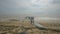 People Stand on Beach in front of Broken Building Sailing in Sea