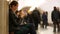 People on the subway platform. Women sitting with a mobile phone while waiting