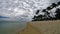 People in a sunny day walking on the public beach of Flic en Flac with tropical trees on edge of Indian Ocean, Mauritius