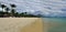 People in a sunny day walking on the public beach of Flic en Flac with tropical trees on edge of Indian Ocean, Mauritius