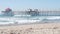 People surfing in ocean waves, Huntington Beach pier, California coast, USA.
