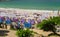 People swimming in the sea on a sunny day, in the foreground there are many rows with sunbeds