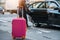 People taking taxi from an airport and loading carry-on luggage bag to the car.