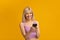 People and technology concept. Overjoyed woman holding and using mobile phone standing on yellow studio background